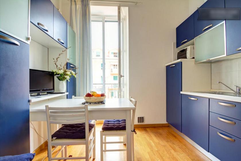 a kitchen with blue cabinets and a table and chairs at Casa Vacanze Oneglia in Imperia
