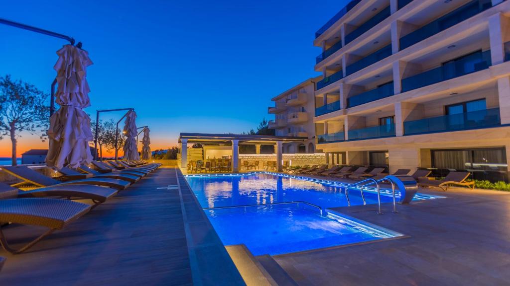 a hotel with a swimming pool and lounge chairs at Luxury Aparthotel Makarska in Makarska