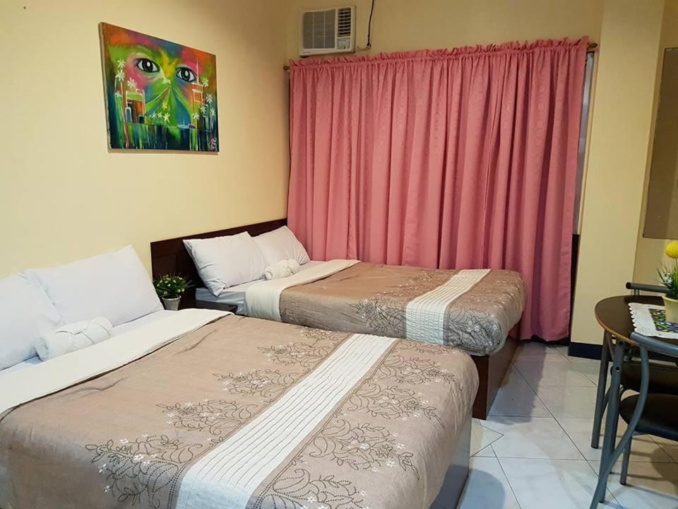 a room with two beds and a table and a window at City Corner Hotel in Legazpi