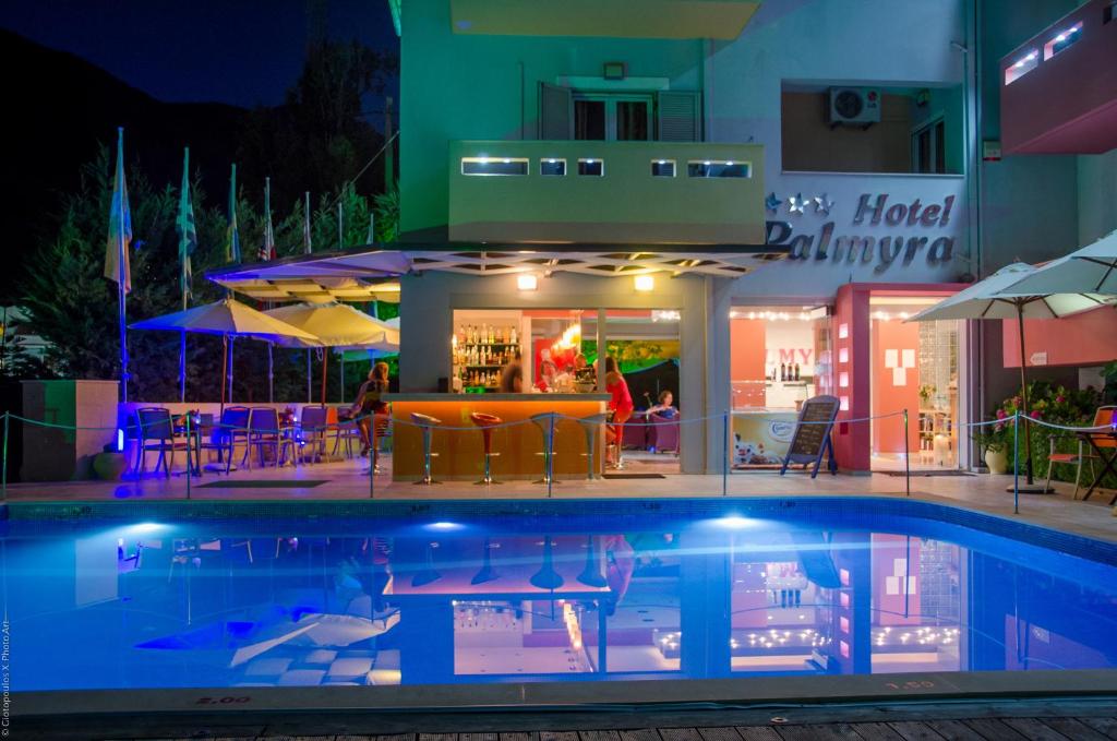 uma piscina em frente a um hotel à noite em Palmyra Hotel em Nydri