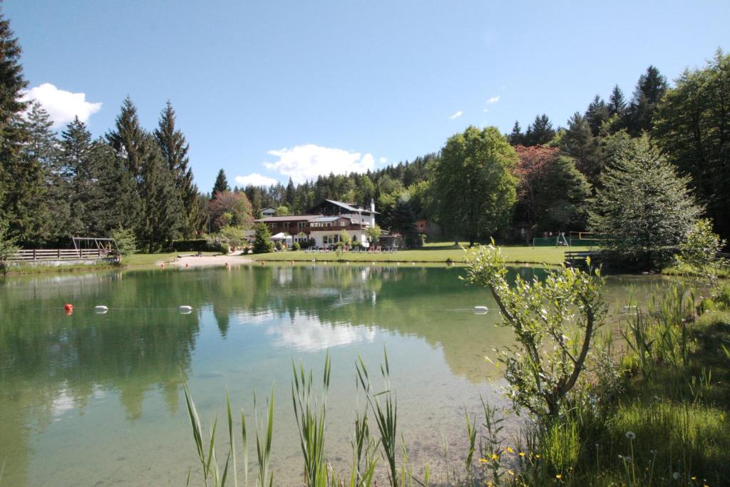 a large lake with a house in the background at Ferienanlage Forellenhof in Ledenitzen