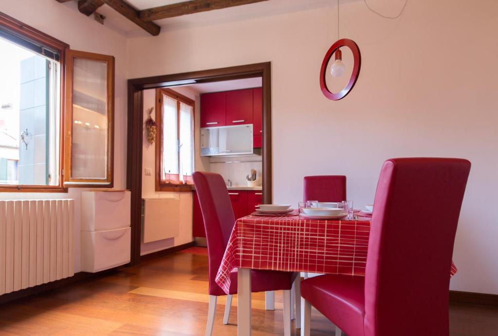 a dining room with a red table and chairs at Appartamento Cà del Bianco 4 in Venice