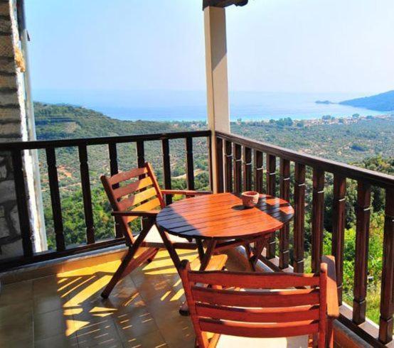 einen Holztisch und Stühle auf einem Balkon mit Aussicht in der Unterkunft Agnanti Studios in Panagia