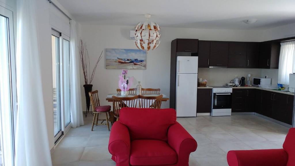 a living room with a red couch and a kitchen at Aegean View Villa in Loutraki
