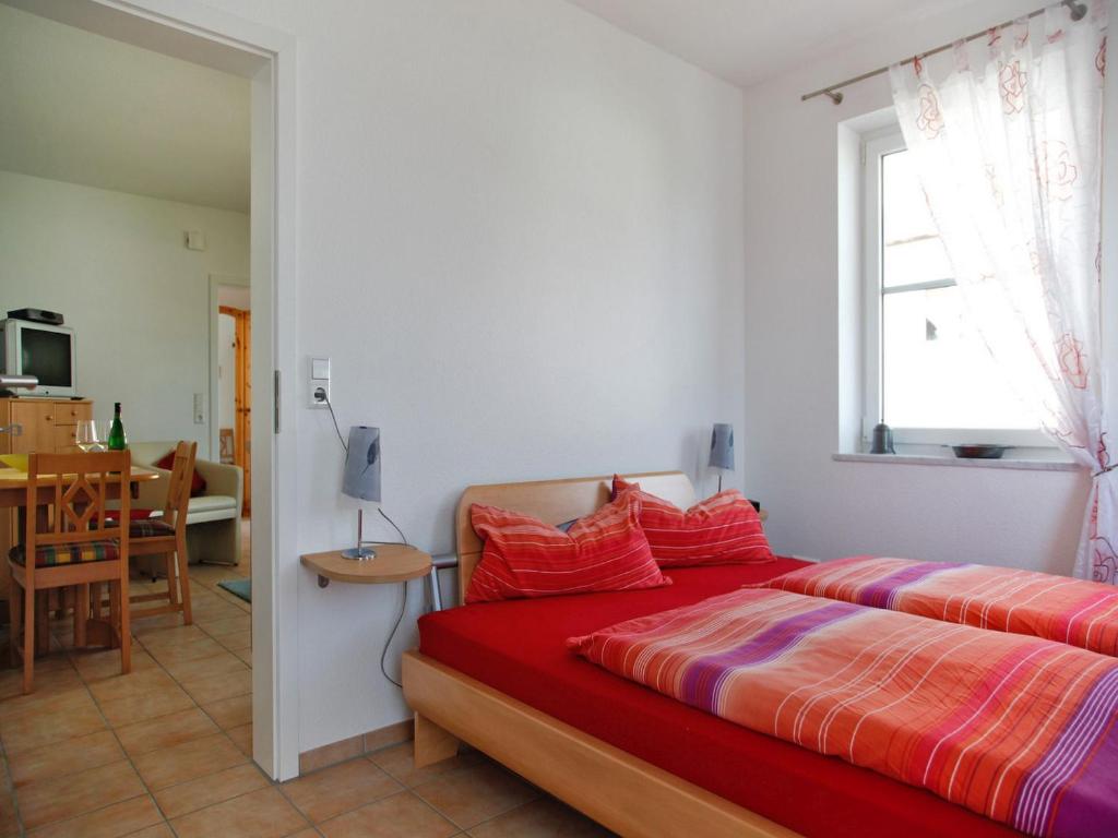 een slaapkamer met een rood bed en een eetkamer bij Ferienwohnung Amann in Nonnenhorn