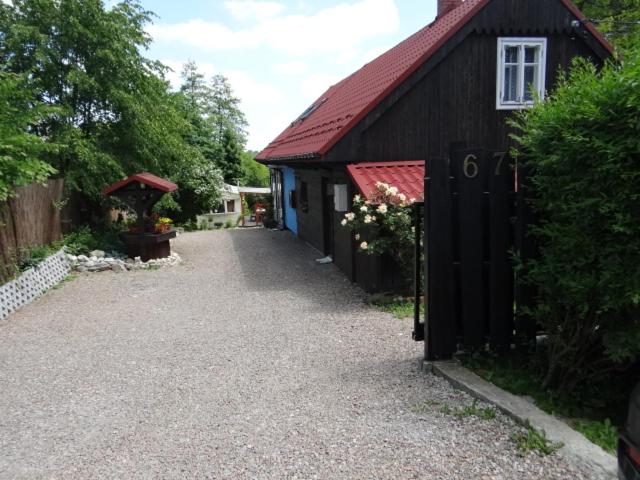 a black barn with a red roof and a gravel driveway at Agroturystyka Dyrdówka in Byszyce