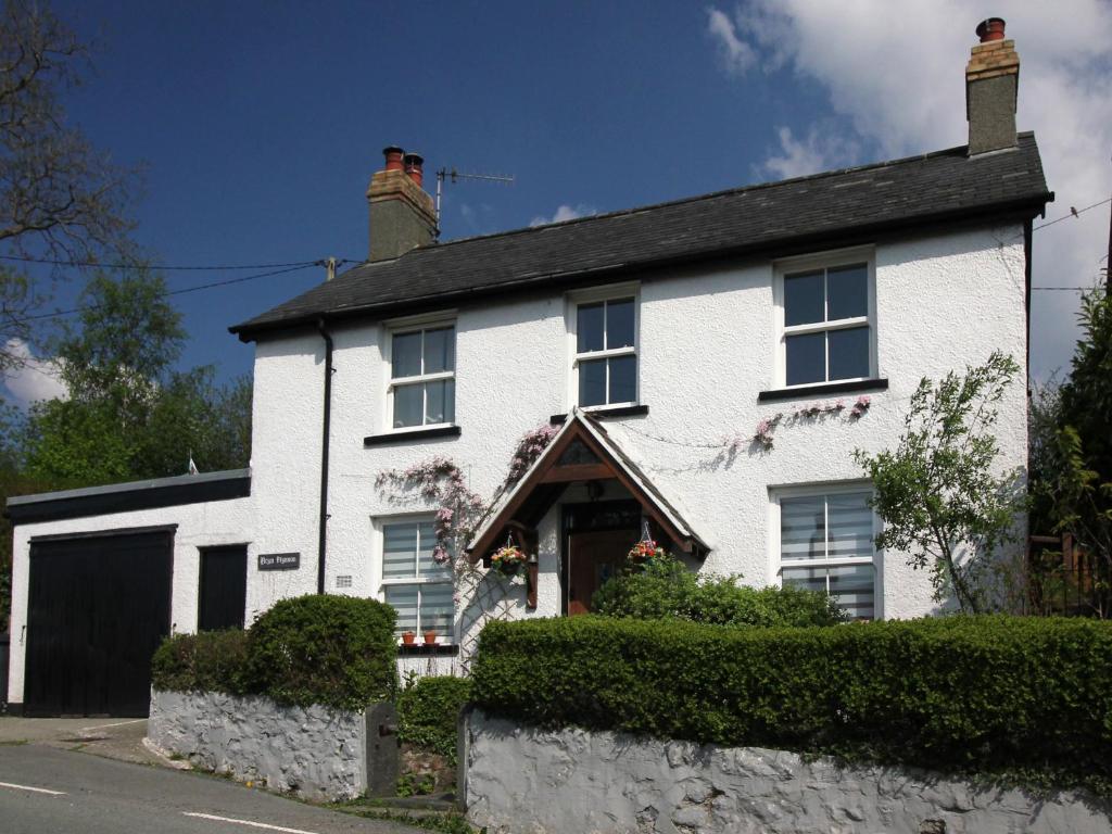 a white brick house with a black garage at Bryn Ffynnon Holiday Cottage Llanrwst in Llanrwst