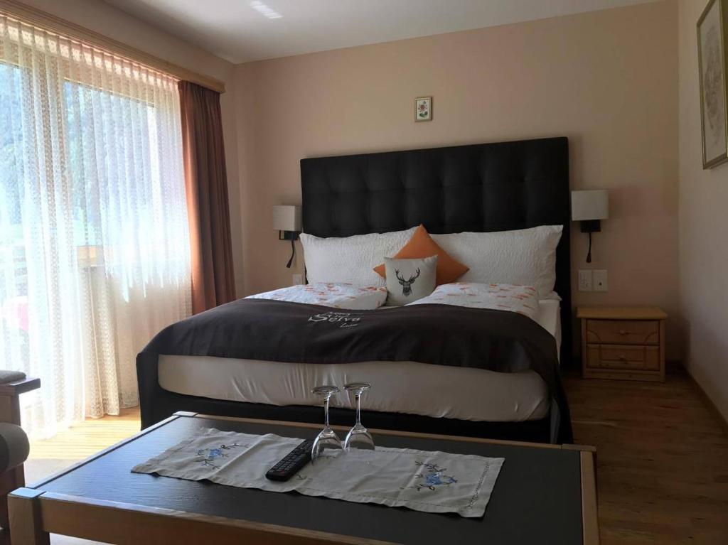 a bedroom with a large bed and a table with glasses on it at Hotel Pizzeria Selva in Zernez