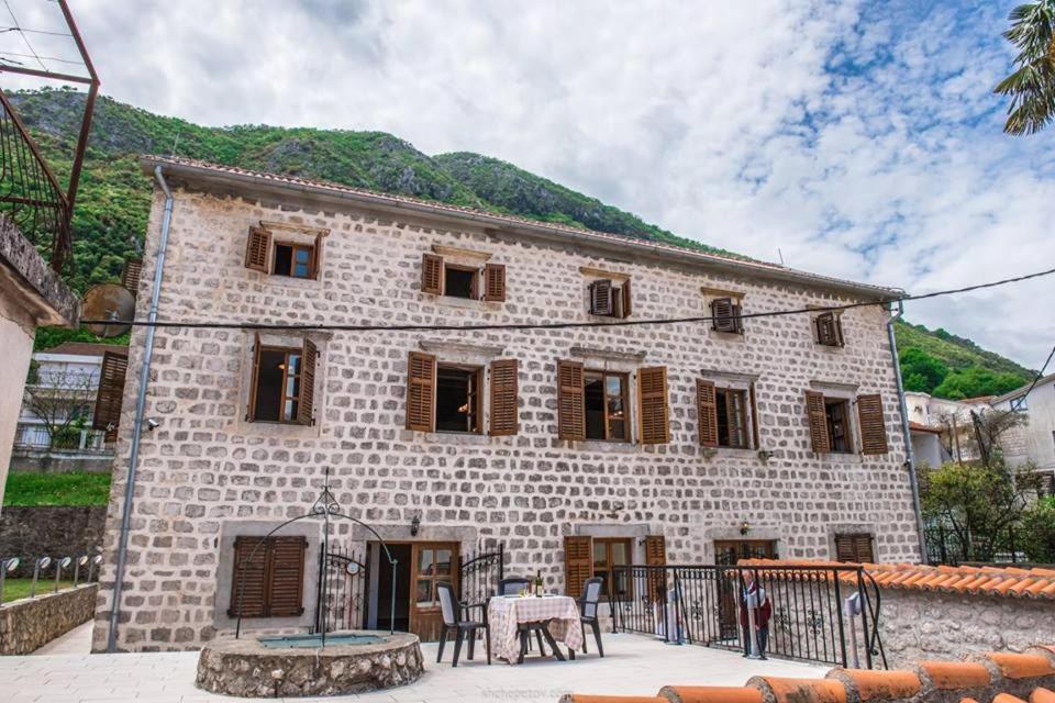 Un grand bâtiment en pierre avec des fenêtres à volets en bois est disponible. dans l'établissement Villa Captain, à Kotor