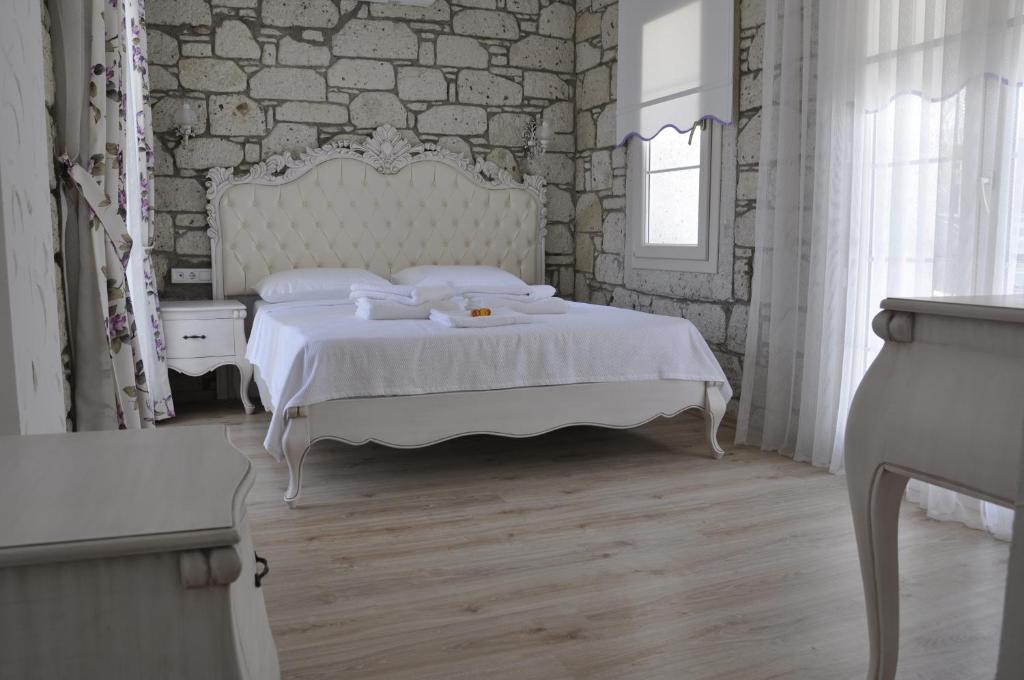 a bedroom with a white bed and a brick wall at Alacati Lucky Angel Hotel in Alaçatı