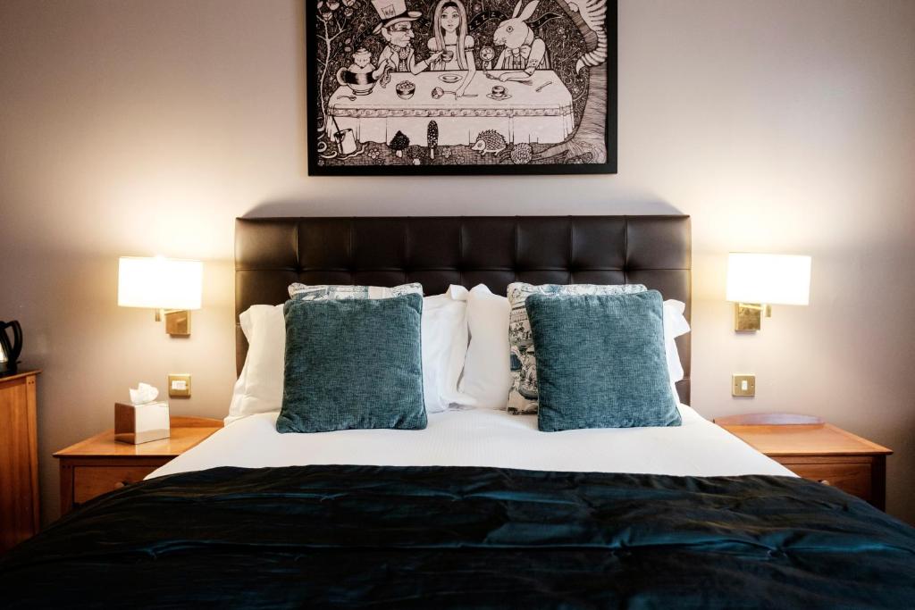 a bedroom with a large bed with blue pillows at The Mad Hatter Hotel in London
