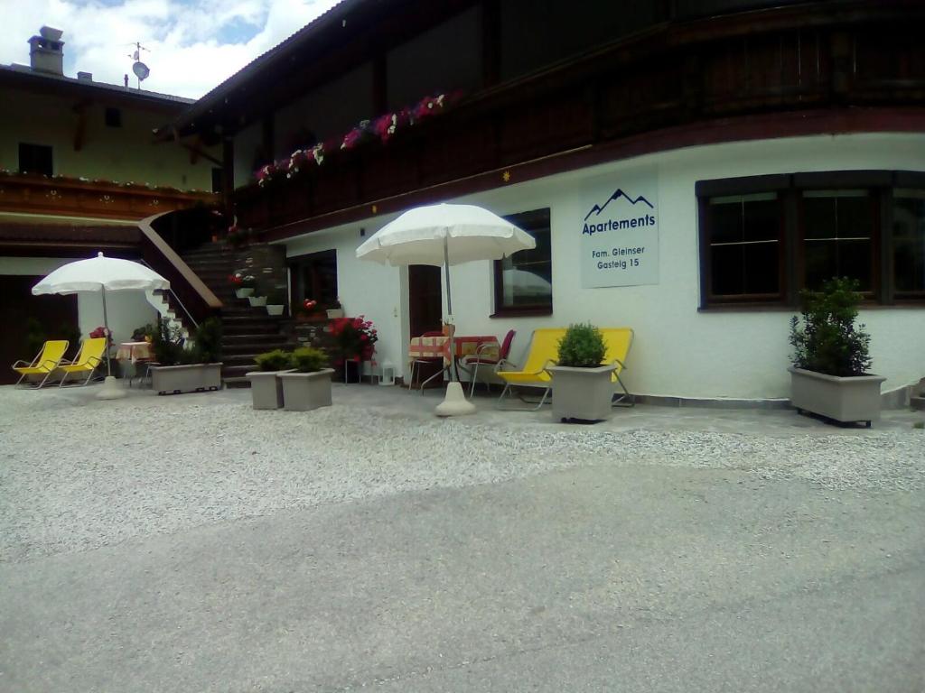 a patio with chairs and umbrellas in front of a building at Appartements Fam. Gleinser Mirella in Neustift im Stubaital