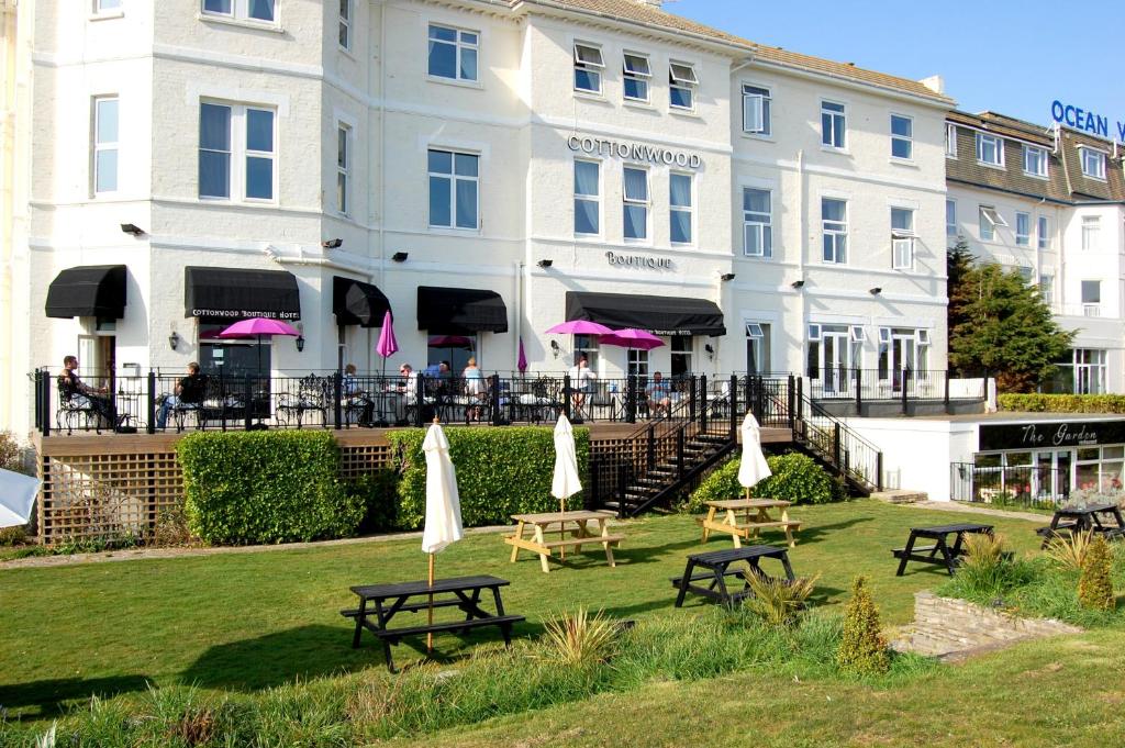 a hotel with tables and umbrellas in front of a building at Cottonwood Boutique in Bournemouth