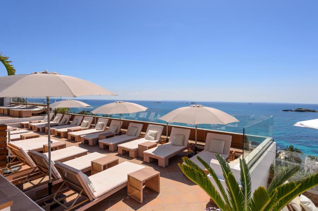 ein Restaurant mit Stühlen und Sonnenschirmen und dem Meer in der Unterkunft Hotel Cenit & Apts. Sol y Viento in Ibiza-Stadt
