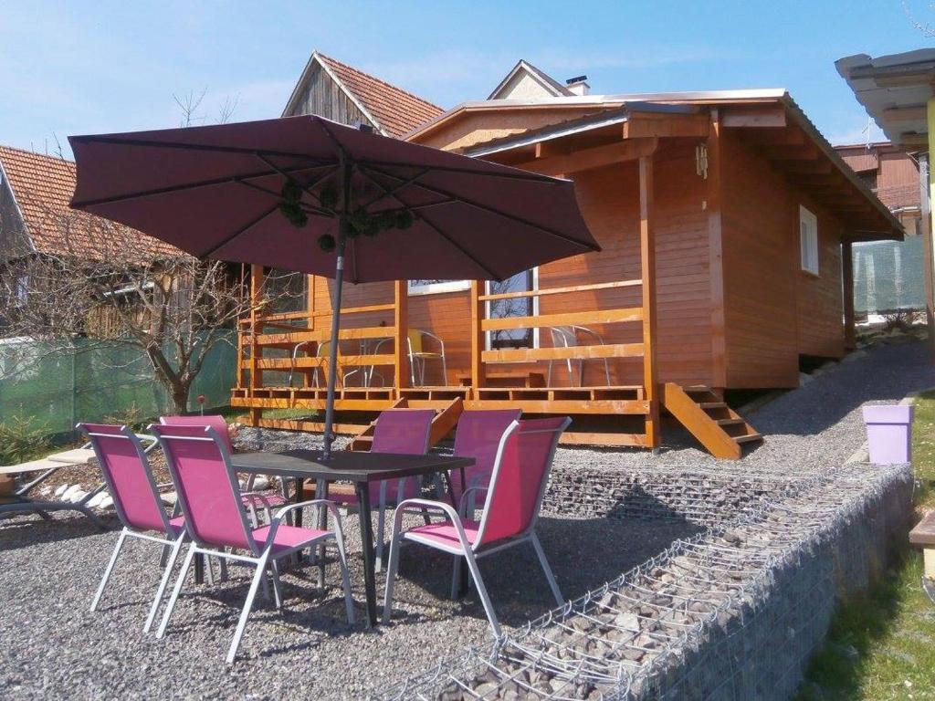 a table with chairs and an umbrella in front of a house at Drevenica Kvietok in Liptovská Kokava