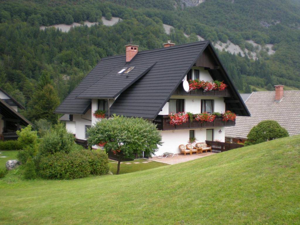 a house with a black roof with flowers on the windows at Apartmaji Vesna in Bohinj