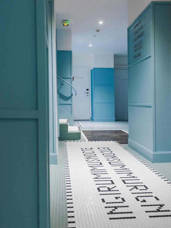 a bathroom with blue walls and a white tile floor at Hotel Eiffel Blomet in Paris
