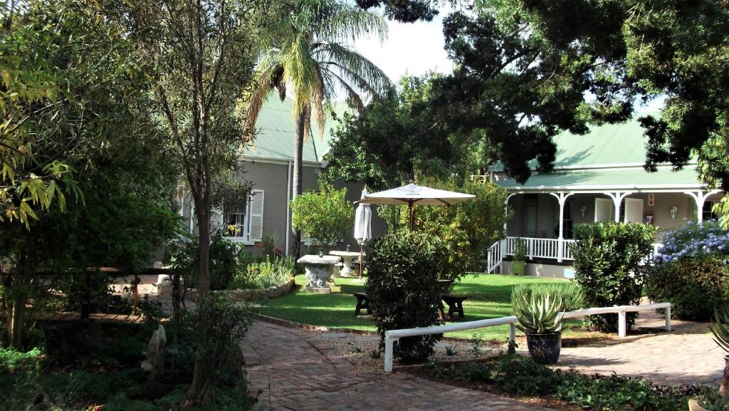 Casa con jardín con mesa y sombrilla en HouseMartin Lodge & Self Catering, en De Rust