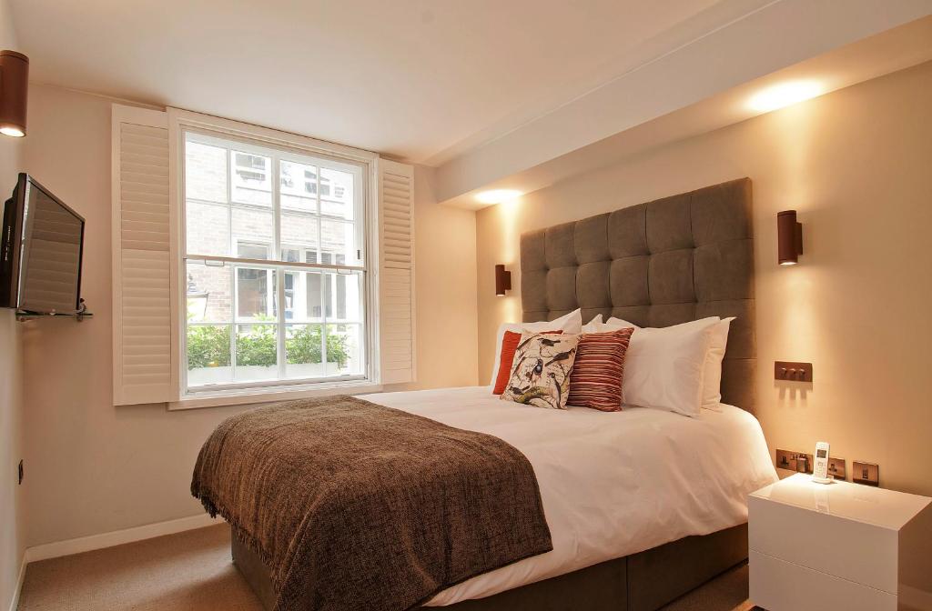 um quarto com uma cama grande e uma janela em Wigmore Suites Serviced Apartments by Globe Apartments em Londres