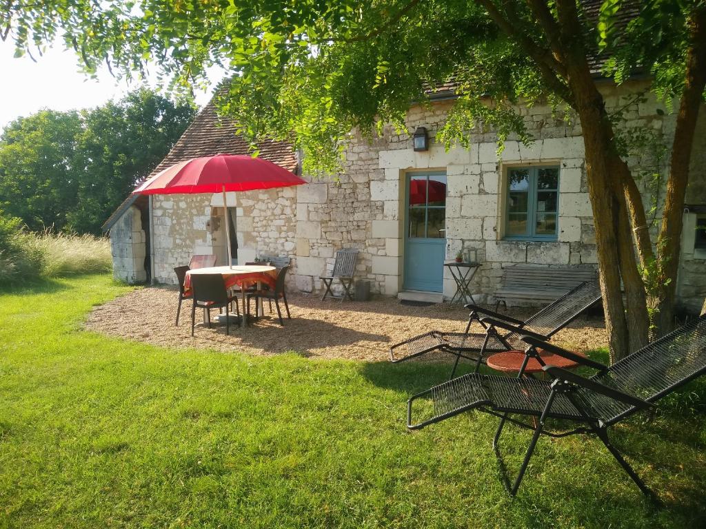 a table with a red umbrella in front of a building at Gite La Bergerie in Varennes
