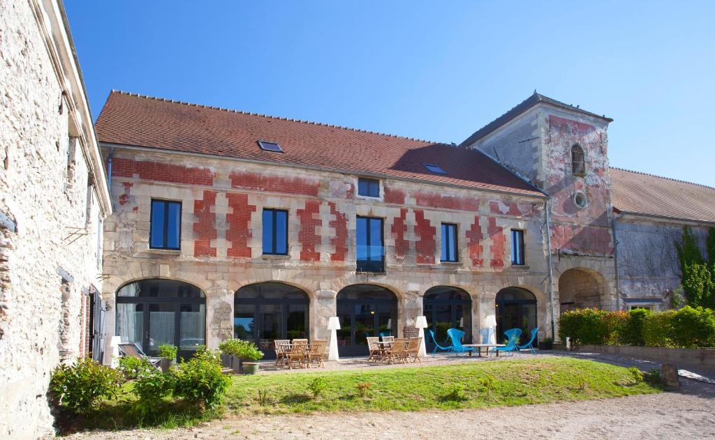 un ancien bâtiment avec des chaises et des tables devant lui dans l'établissement Les Tournelles - Chambres d'hôtes, à Saint-Mesmes