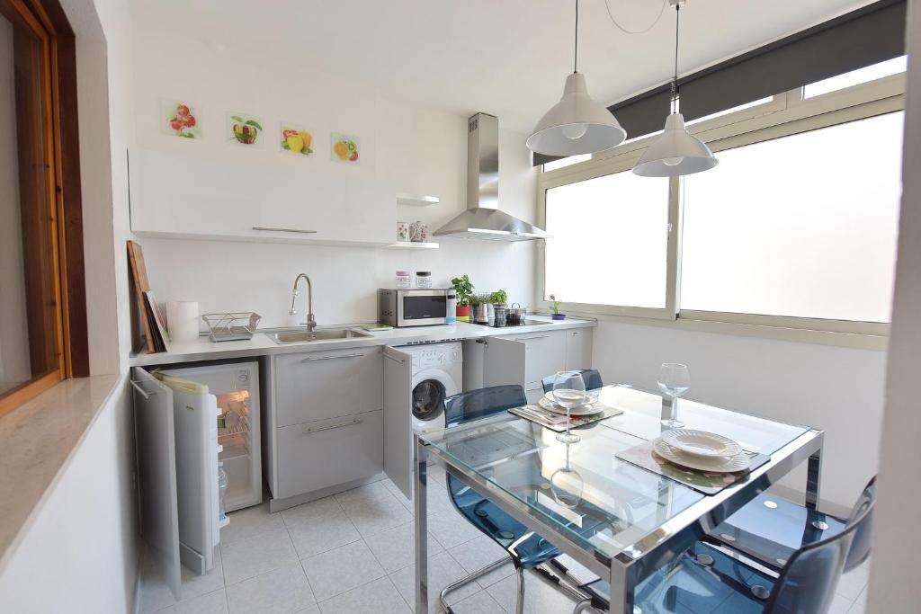 a kitchen with a glass table and a dishwasher at Stella Marina in Quartu SantʼElena