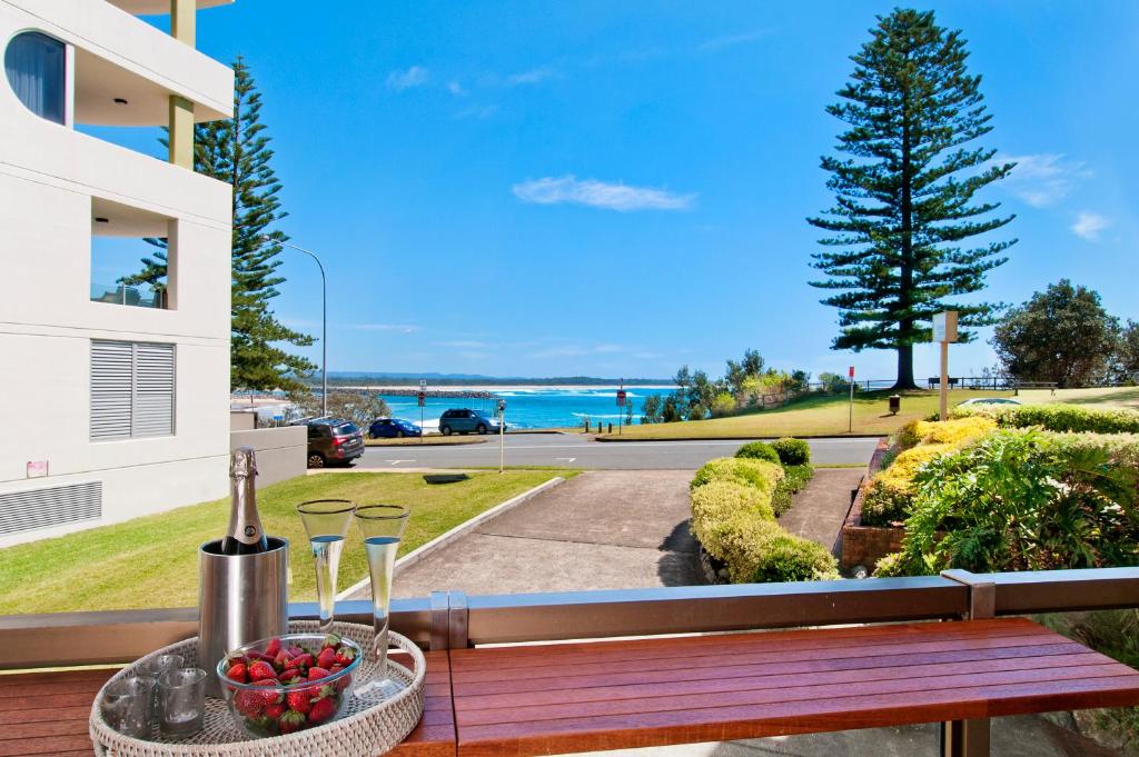 a bowl of fruit sitting on a table on a balcony at Beauty at the Beach - modern beachfront apartment in Port Macquarie