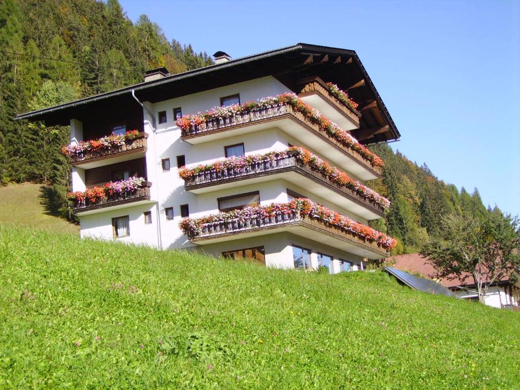 a building on a hill with flowers on the balconies at Haus Strieder in Maria Luggau
