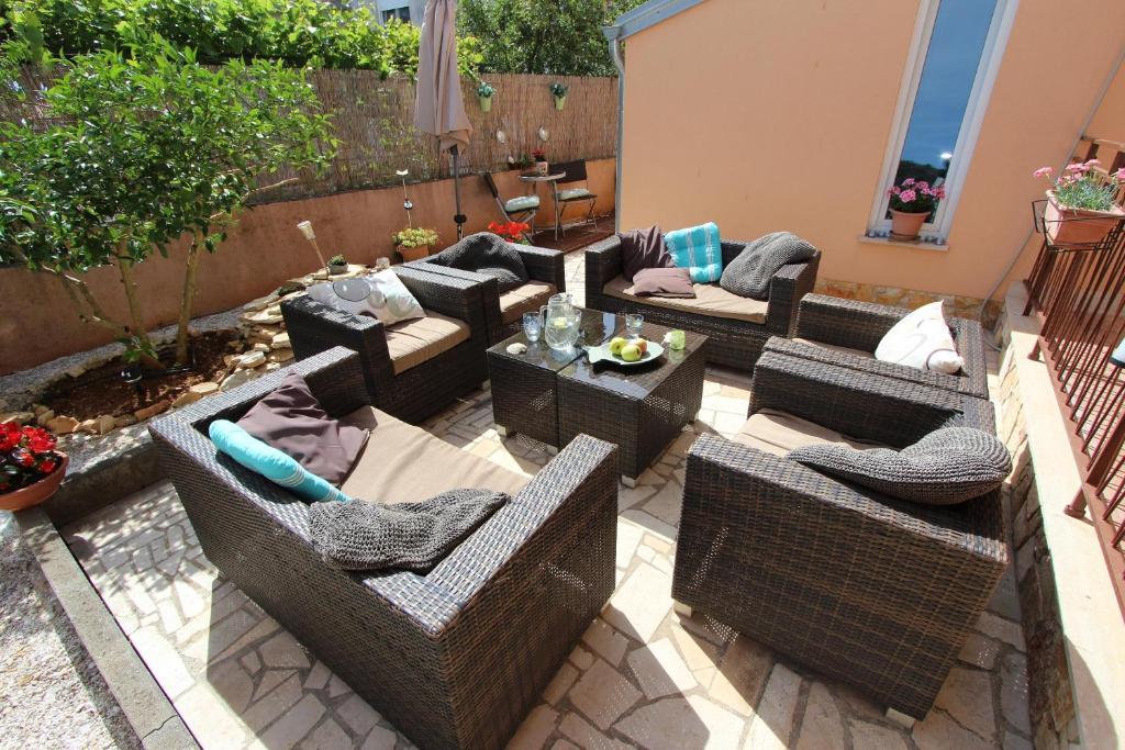 un patio extérieur avec des chaises et des tables en osier dans l'établissement Apartments Villa Nikola, à Rovinj