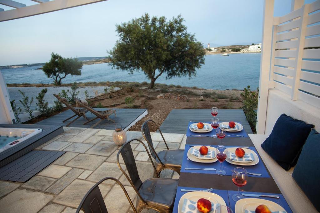 a table with plates of food on a patio with a view of the water at Kalypso Villas in Naousa