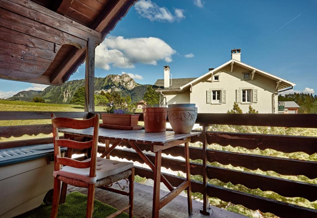 einen Tisch und einen Stuhl auf einem Balkon mit einem Haus in der Unterkunft Le Liseron in Leysin