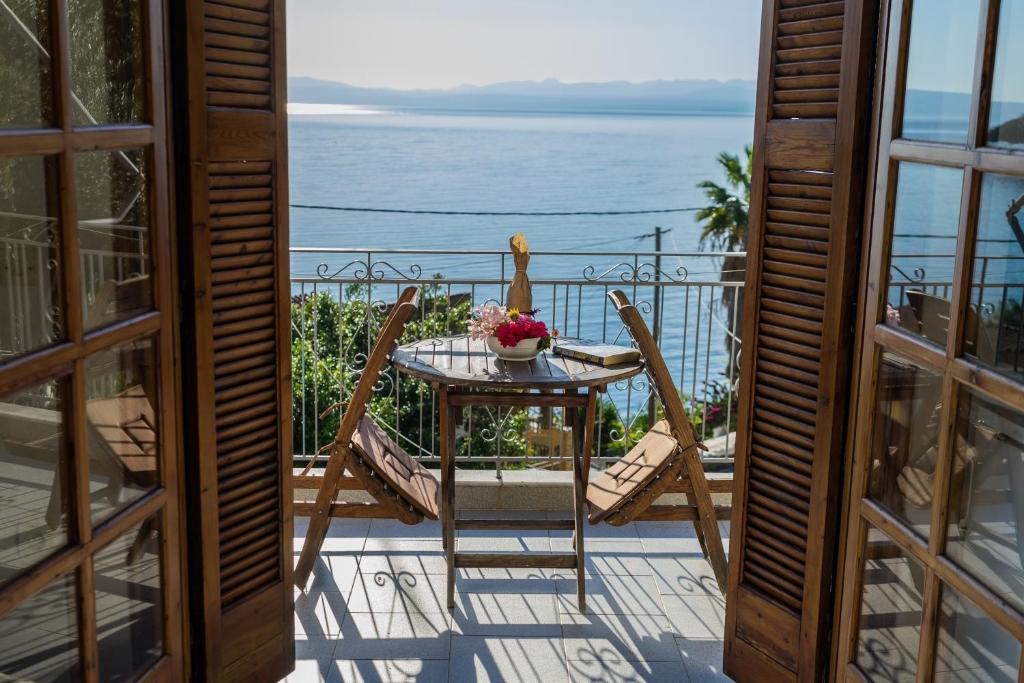 una mesa y sillas en un balcón con vistas al océano en Studios Koukis, en Kitriaí