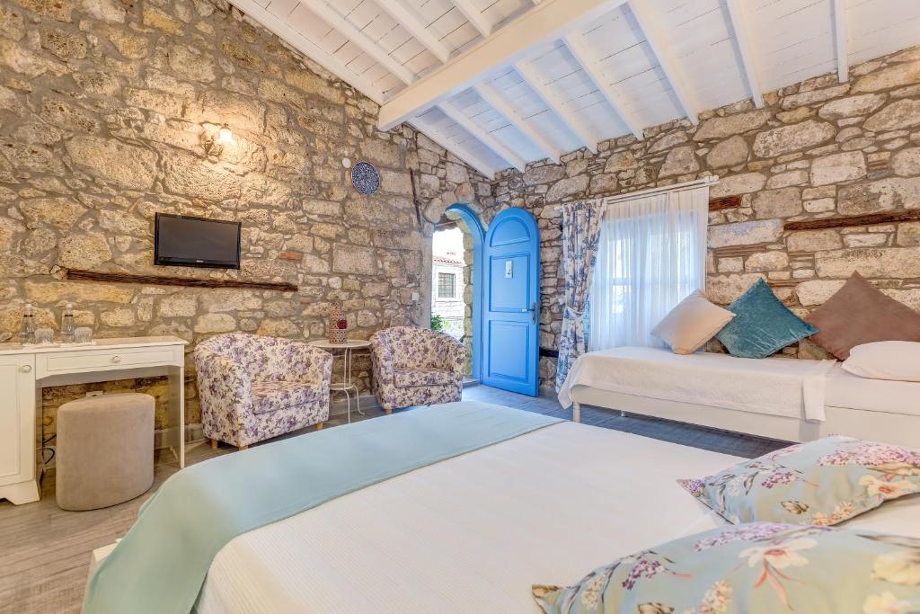 a bedroom with a bed and a tv in a stone wall at Alacati Eski Ev Hotel in Alaçatı