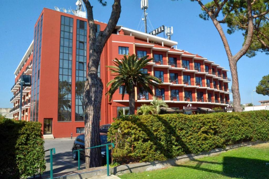 un edificio rosso con una palma di fronte di Park Hotel a Latina