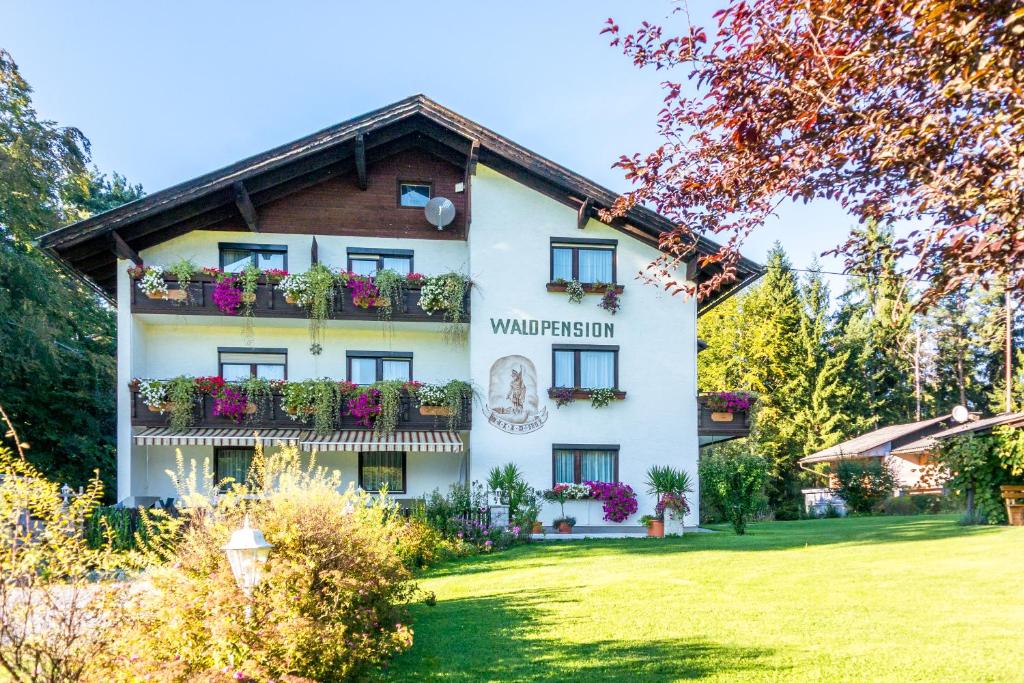 ein weißes Gebäude mit Blumen an den Fenstern in der Unterkunft Waldpension Schiefling am See in Schiefling am See