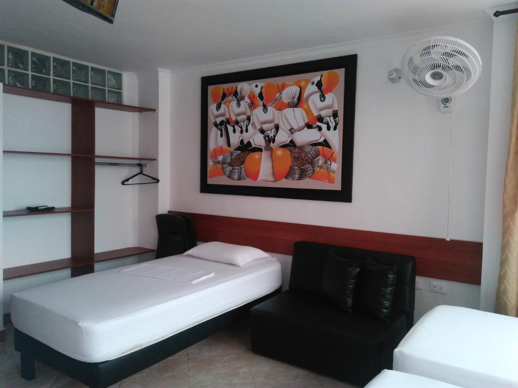 Habitación con cama, silla y pintura en Apartamentos Freddy's Tours, en Santa Marta