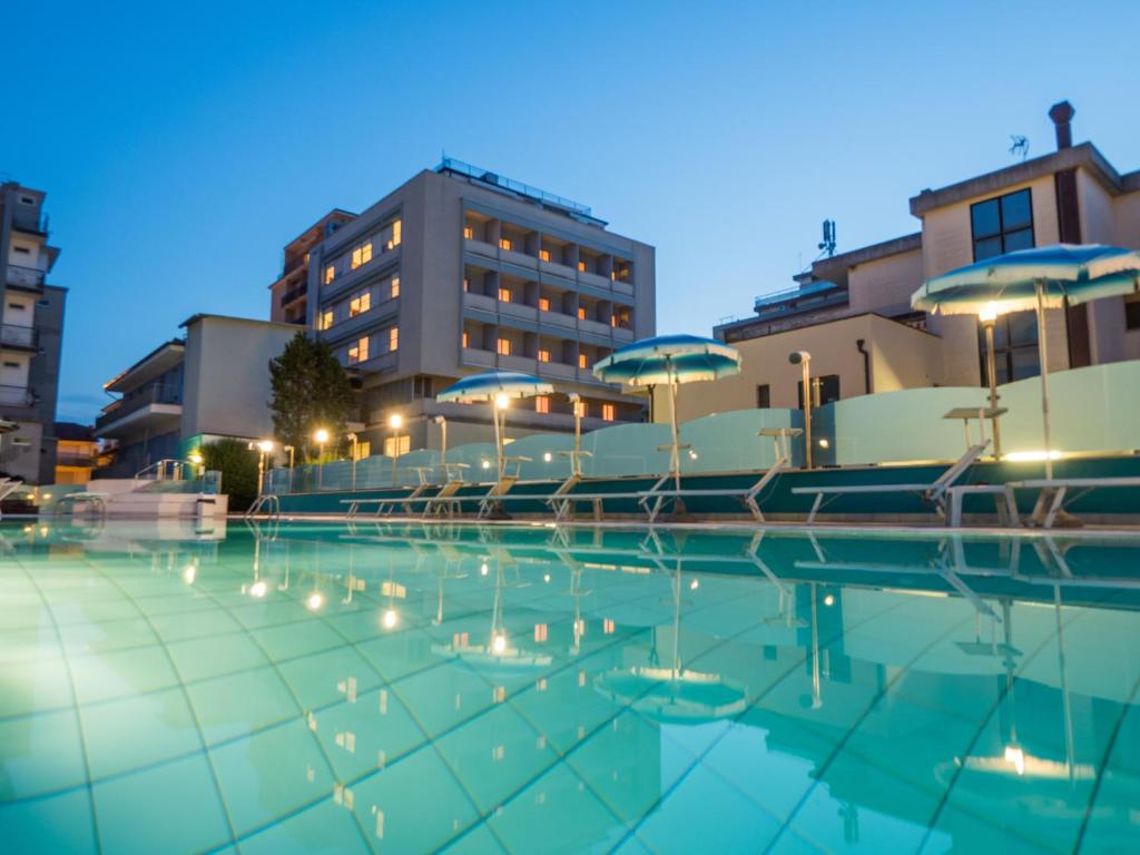 - une piscine avec des parasols, des chaises et des bâtiments dans l'établissement Hotel Ras, à Gatteo a Mare