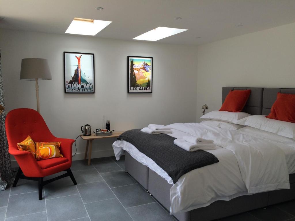 um quarto com uma cama e uma cadeira vermelha em The Garage em Banbury