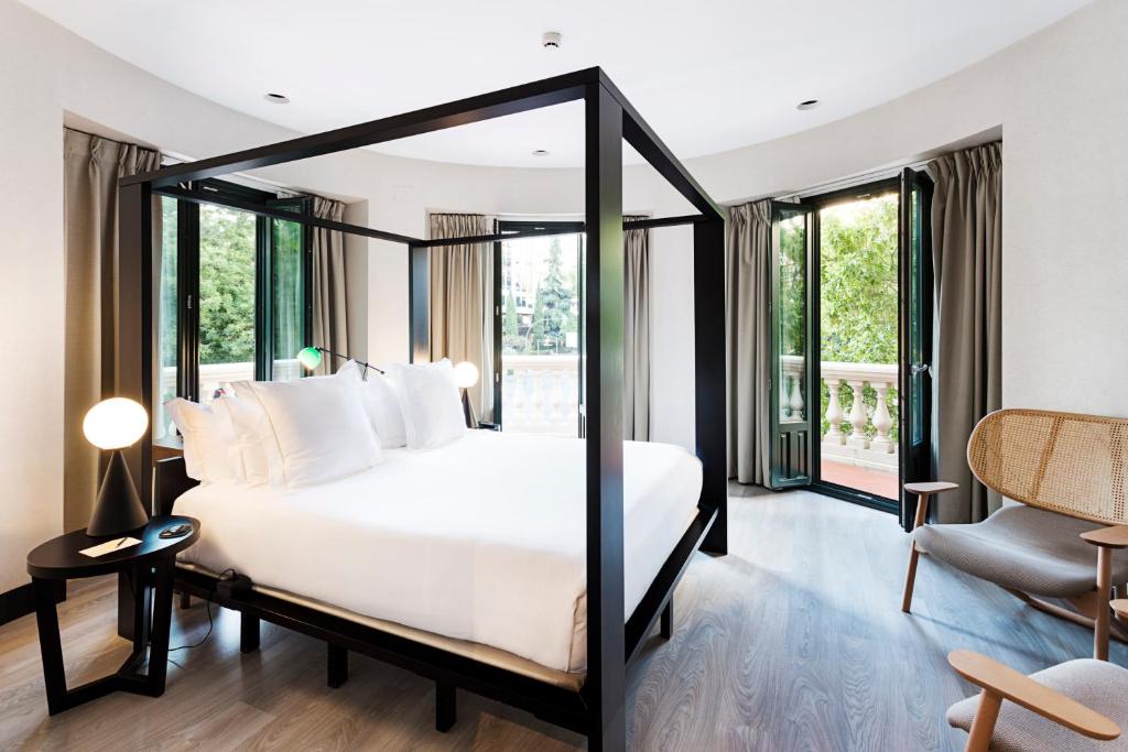 a bedroom with a white bed and large windows at One Shot Luchana 22 in Madrid