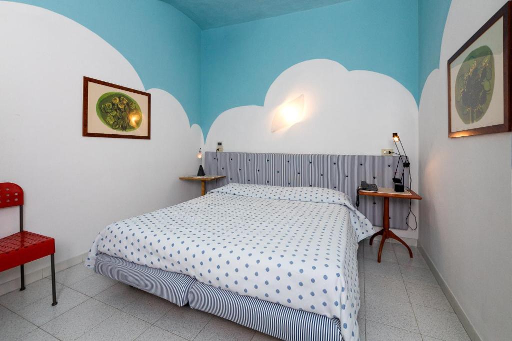 a room with a bed, a desk and a painting on the wall at Hotel Il Falchetto in Pontedera