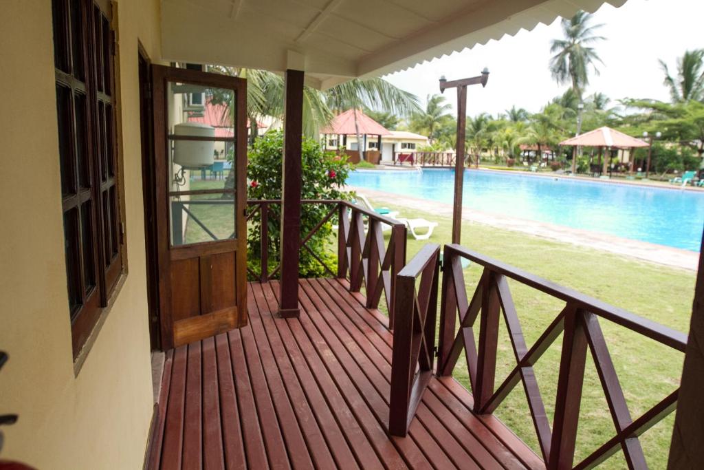 a wooden porch with a door next to a pool at Praia Accommodation in São Tomé