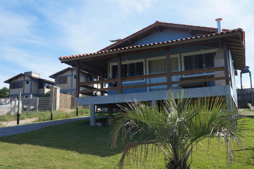 uma casa na praia com uma palmeira em frente em PDR Casas em Praia do Rosa