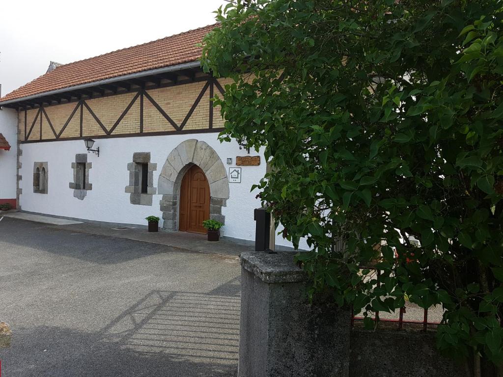 un edificio blanco con una puerta marrón y un árbol en Casa Rural Oihan - Eder, en Espinal-Auzperri