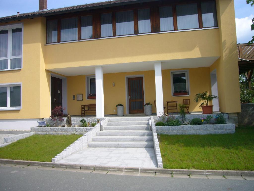 uma casa amarela com escadas em frente em Ferienwohnung im alten Schulhaus - keine Monteure em Plech