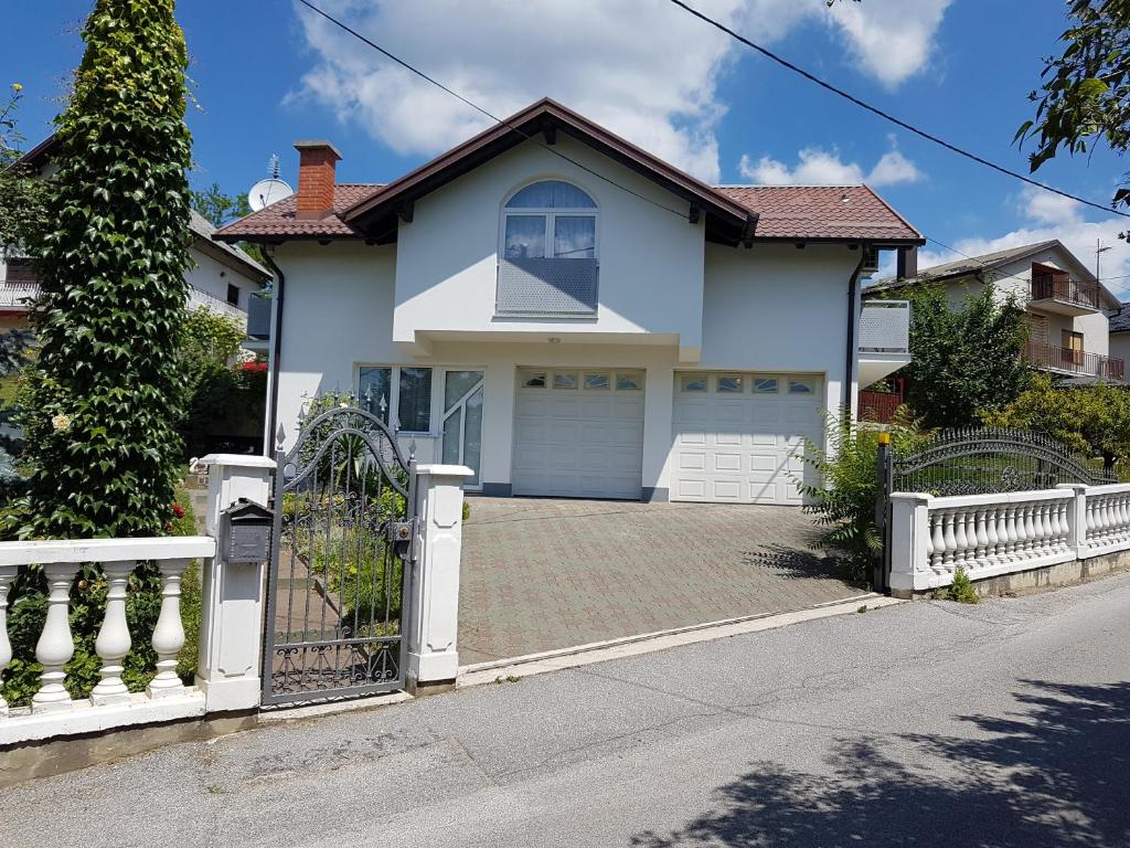 a white house with a gate and a driveway at Apartmani Hršak in Krapina