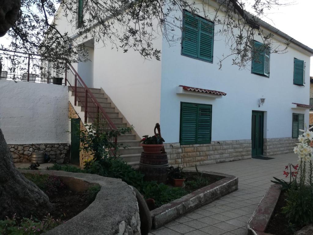 Casa blanca con ventanas con contraventanas verdes y patio en Apartment Bonaca en Lun