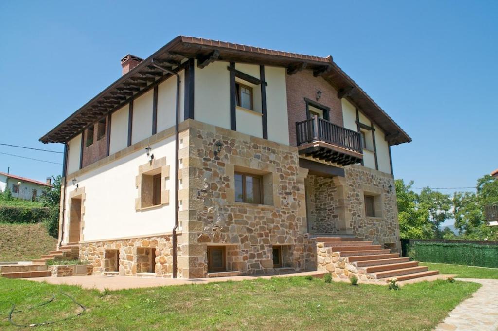 una vecchia casa in pietra con balcone in cima di Casa Aingeru a Carranza