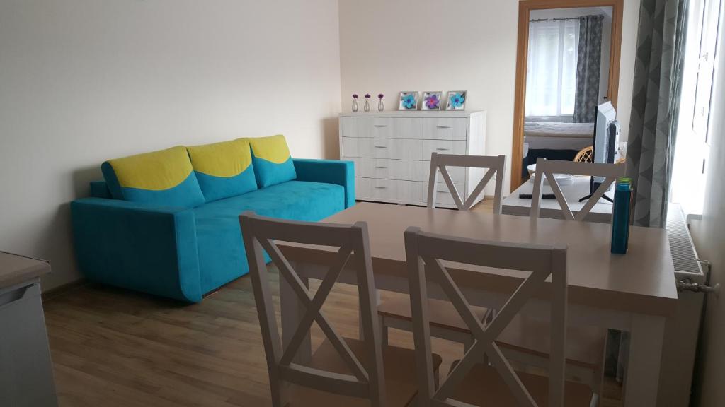 ミエンジズドロイェにあるApartamenty Morska Bryzaのリビングルーム(青いソファ、テーブル、椅子付)