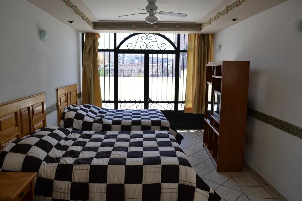 um quarto com 2 camas e uma grande janela em Hotel Senorial em San Juan de los Lagos