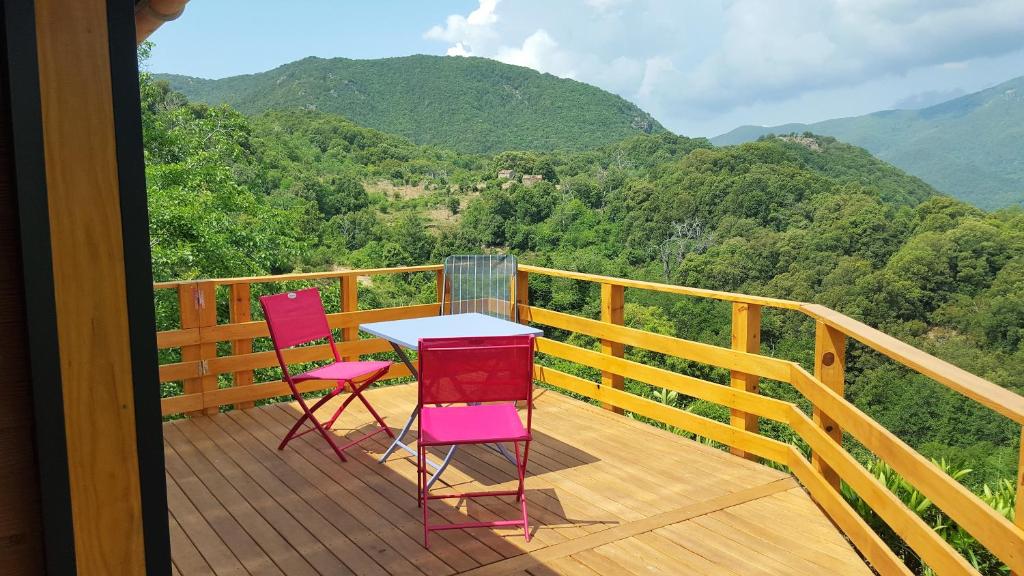 two chairs and a table on a deck with mountains at les chalets et gite du haut taravo in Zicavo